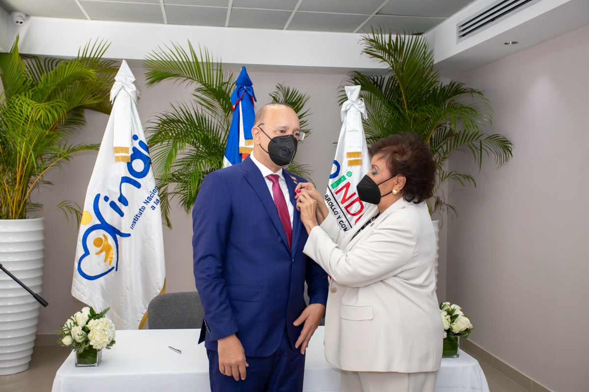 Manola Santana de Báez coloca el pin institucional del Inaipi a Ulises Rodríguez, director de Proindustria