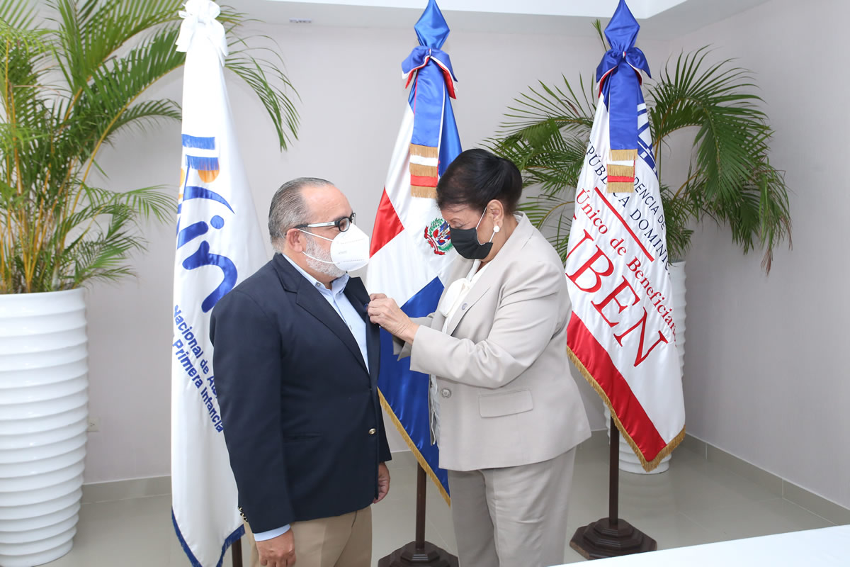 Besaida Manola Santana le colocó el pin institucional a Jefrey Lizardo, director del Siuben, que lo declara hijo distinguido del Inaipi.