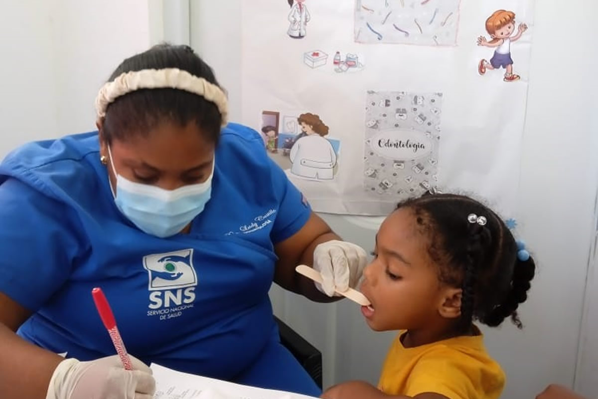 Colaboradora del Servicio Nacional de Salud atendiendo salud bucal a una niña del Centro