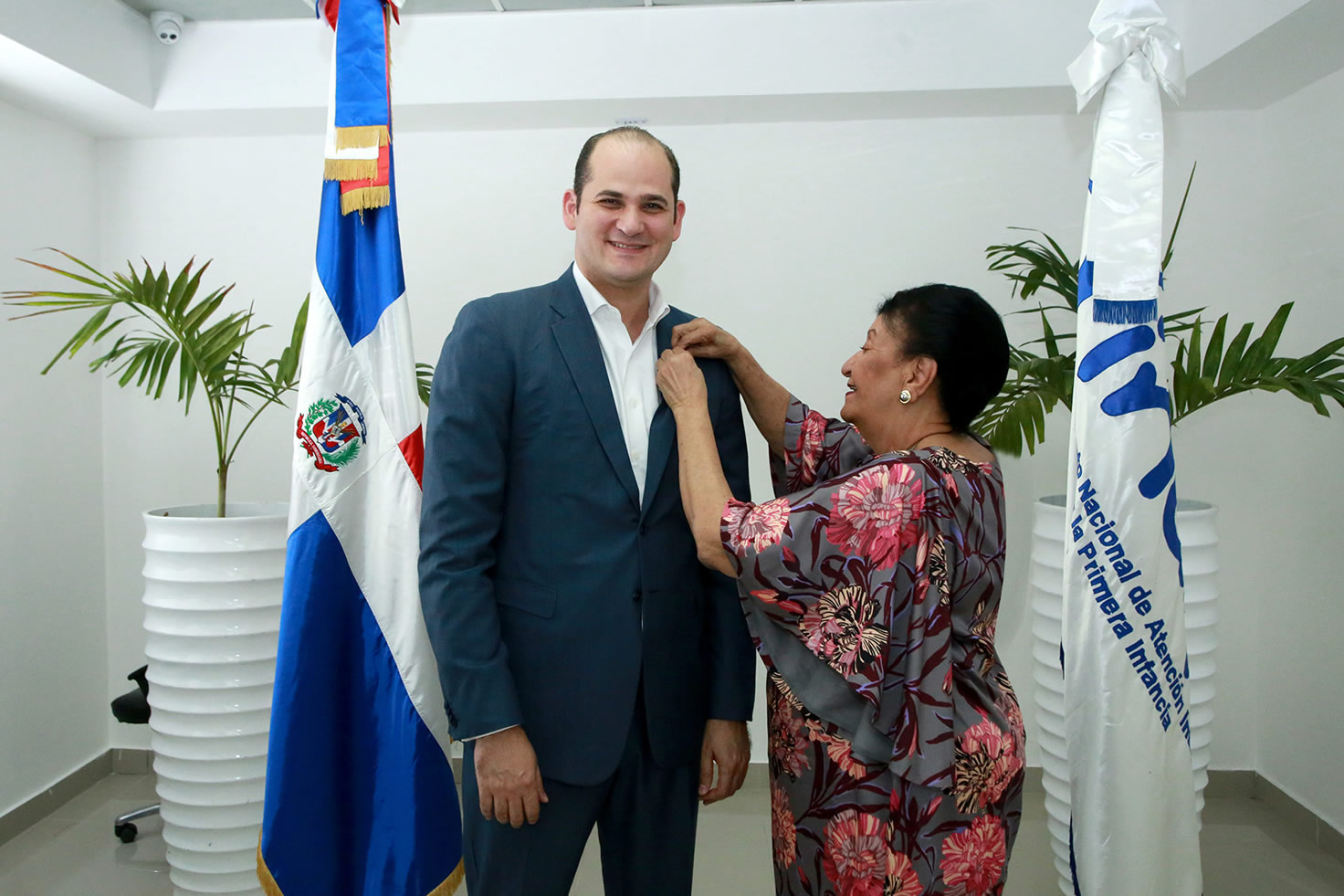 Besaida Manola Santana, directora del INAIPI coloca pin institucional a Adolfo Pérez, director de PROMESE/CAL 