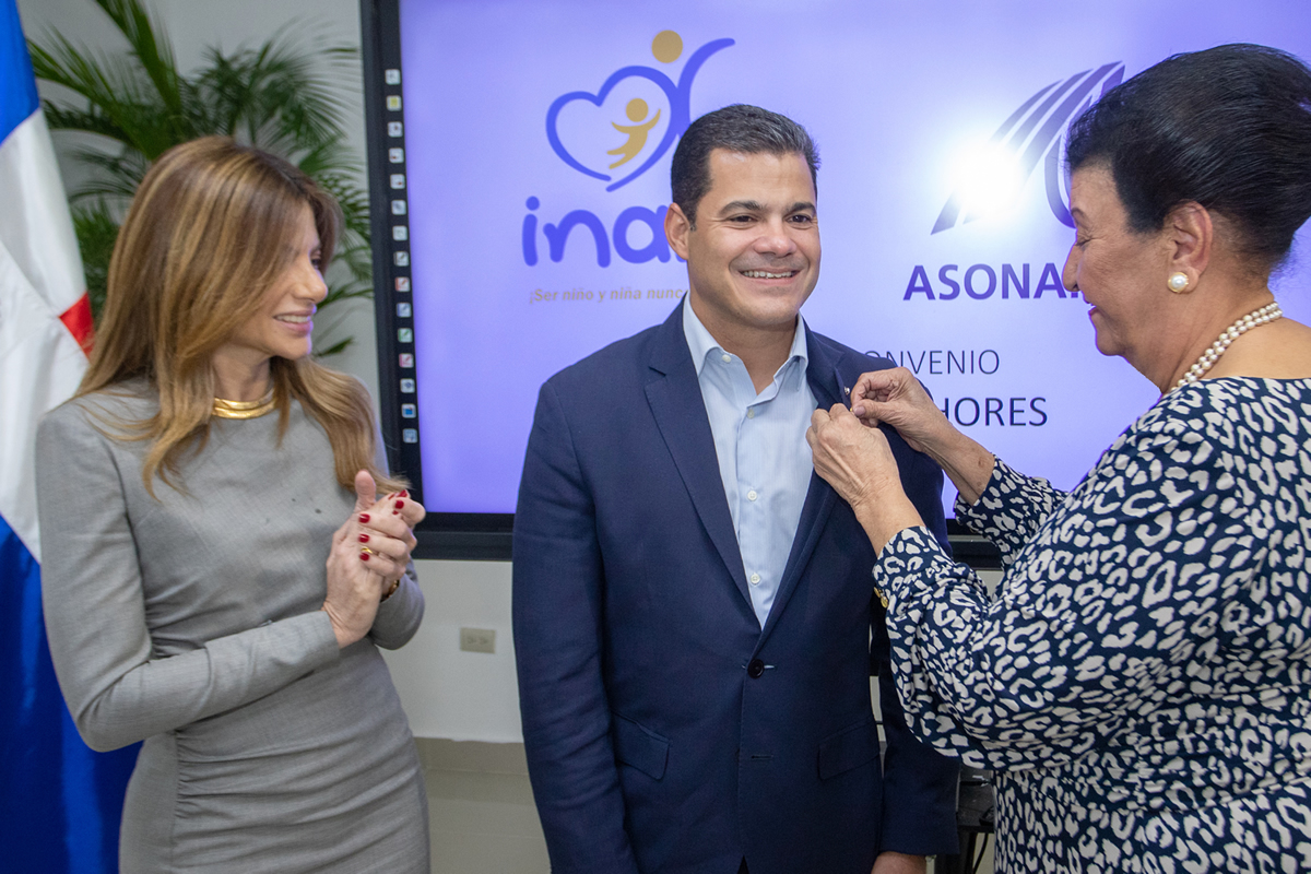 Besaida Manola Santana, directora ejecutiva del INAIPI coloca pin institucional a David Llibre, presidente de ASONAHORES