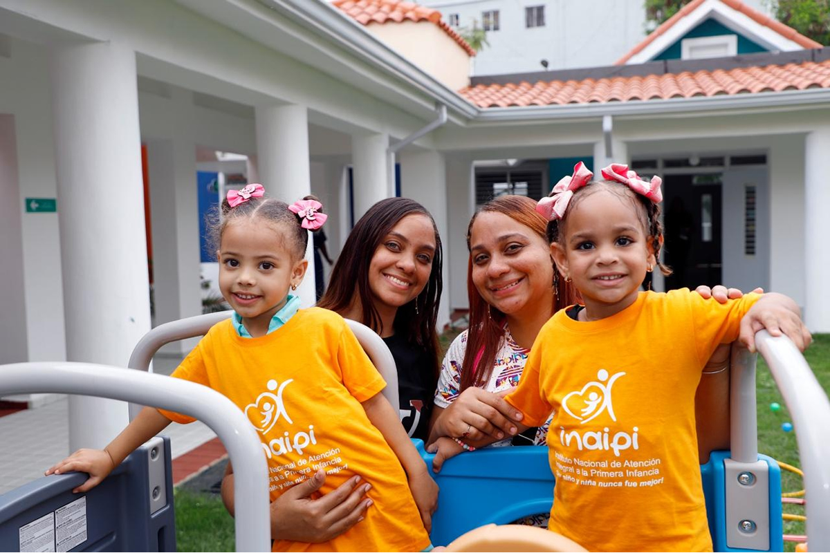 Dos niñas junto a sus tutores en el patio del nuevo Centro CAIPI Guaricano I
